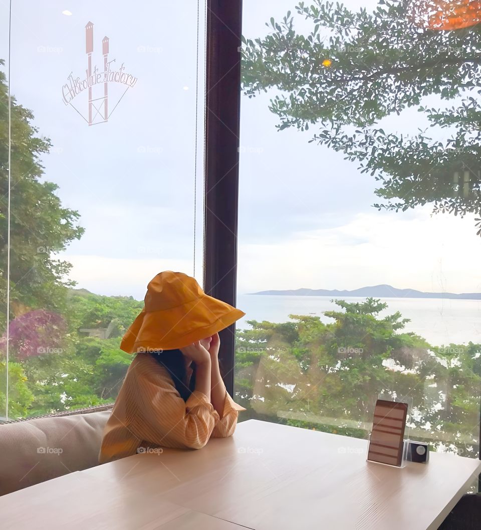 yellow hat girl sit alone side of window