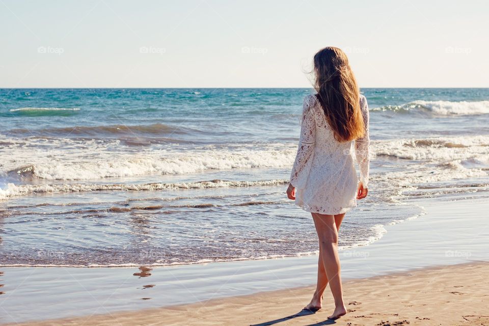 The girl walking over the hot sand and moving towards the sea and feeling the fresh air and sound of water wave. That feeling of beautiful nature