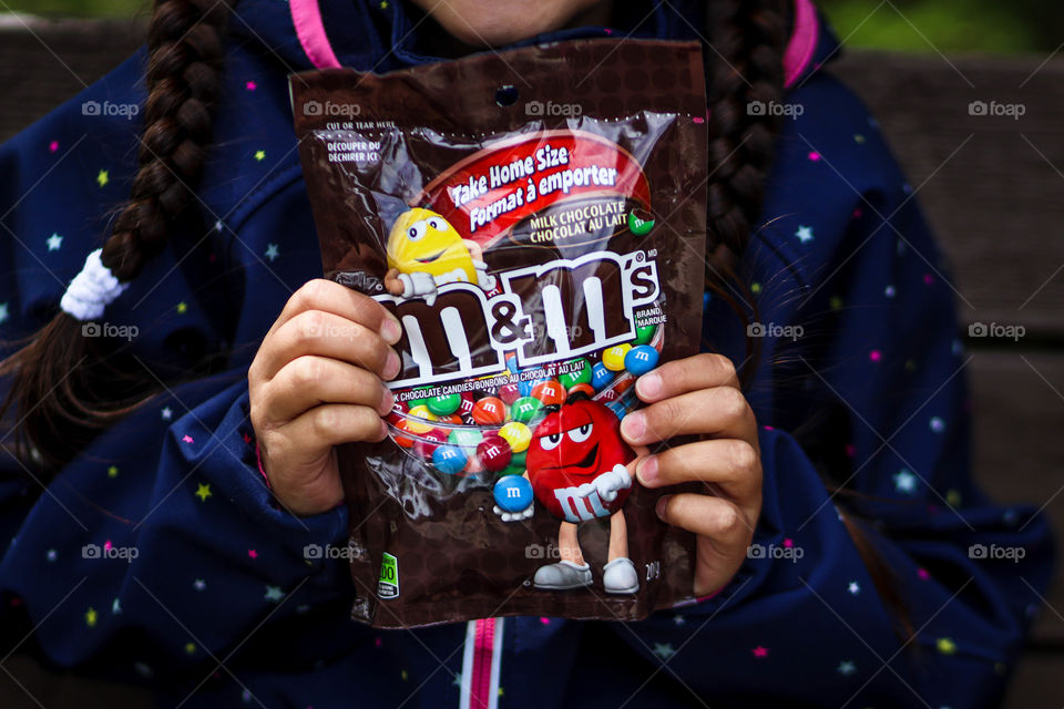 Little child is holding pack of M&Ms chocolates