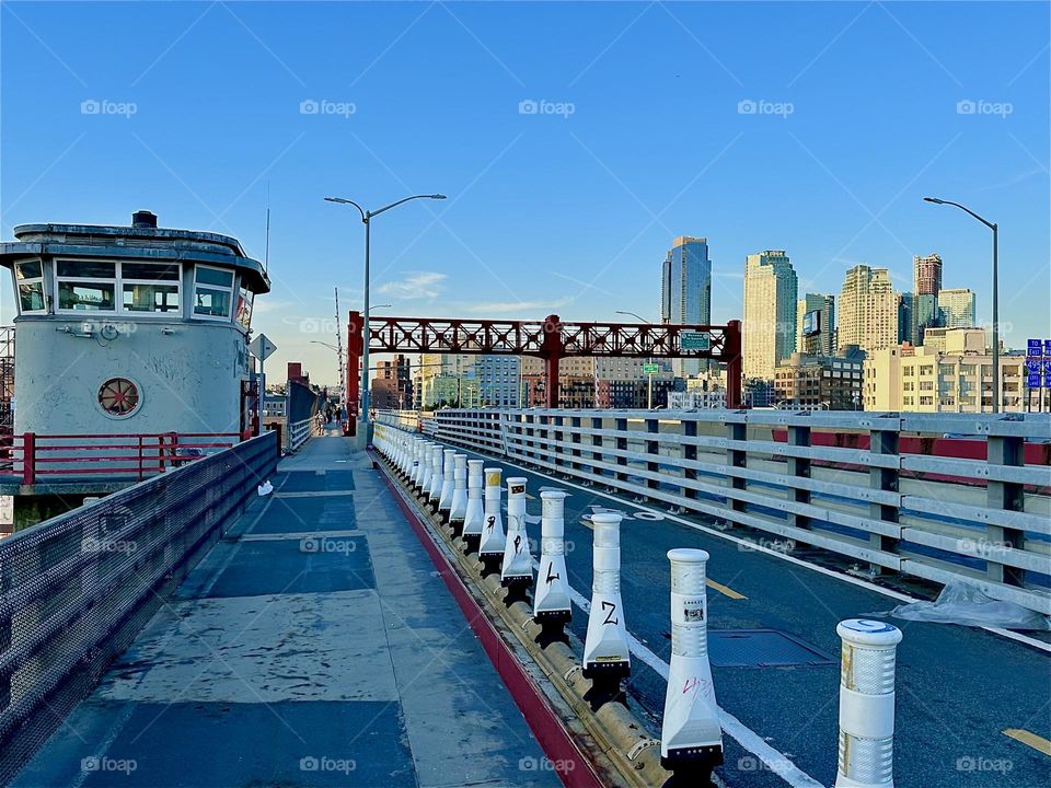 This is the pedestrian and bicycle lane of the “Pulaski Bridge” at “Newtown Creek” connecting “Greenpoint”, Bklyn to LIC in the direction we are headed. The aerodynamic streamlined design reminds of the “Bauhaus” style. 2024. Hypnotic Productions