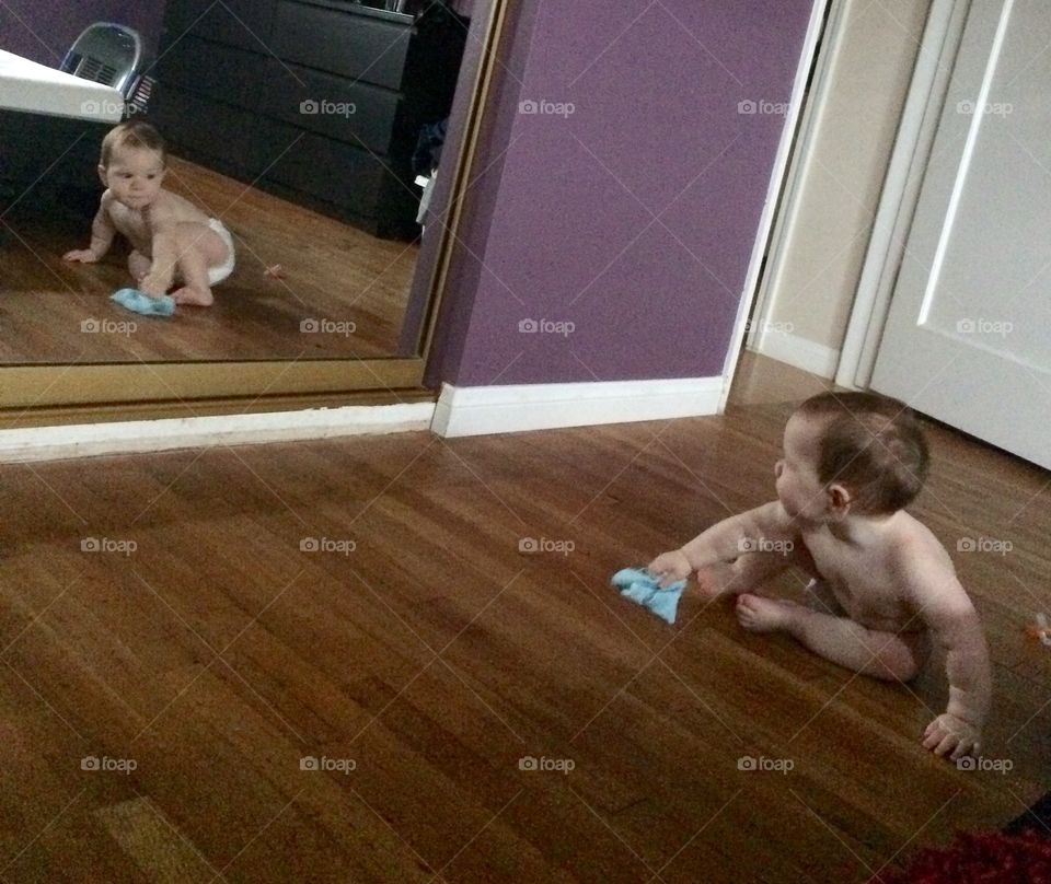 Baby on hardwood floor and reflected in mirror