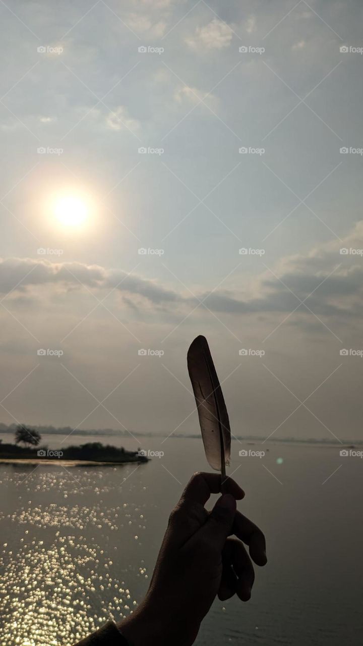 beautiful feather in hand lakeside.