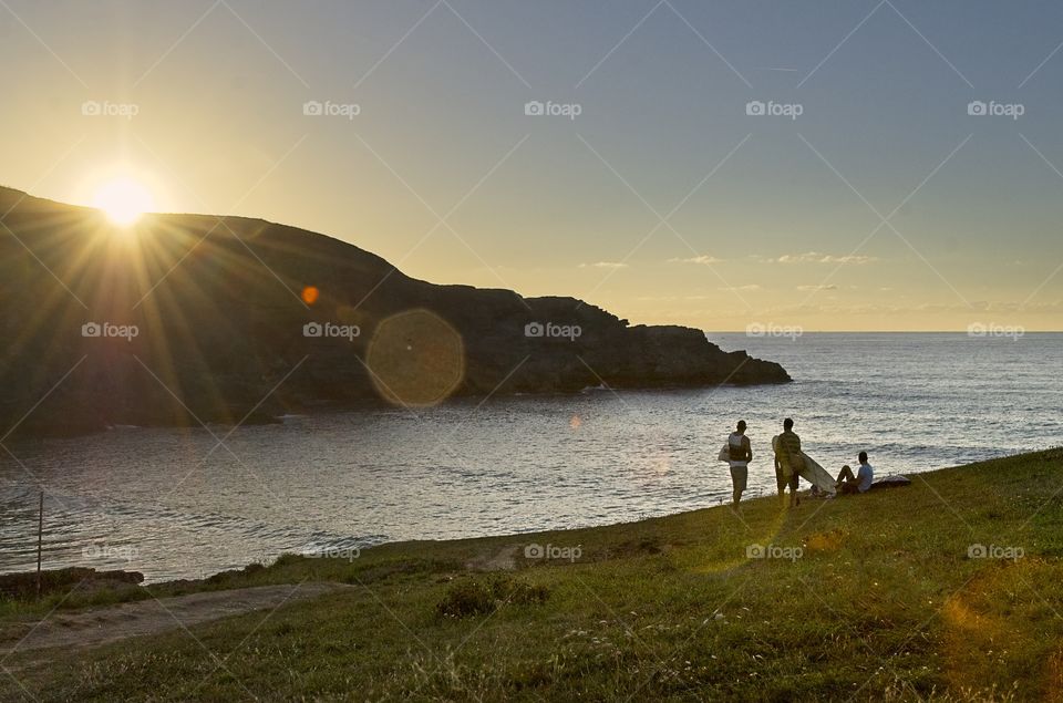 Group of surfers contemplate the sunset on a beach in Spain