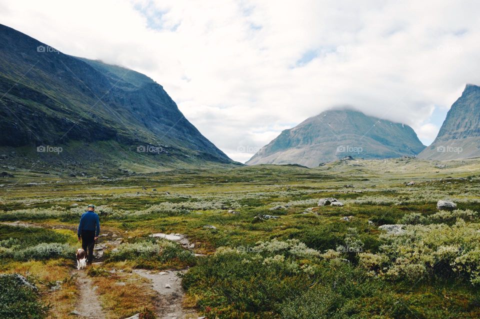 A man walking his dog in mountains 