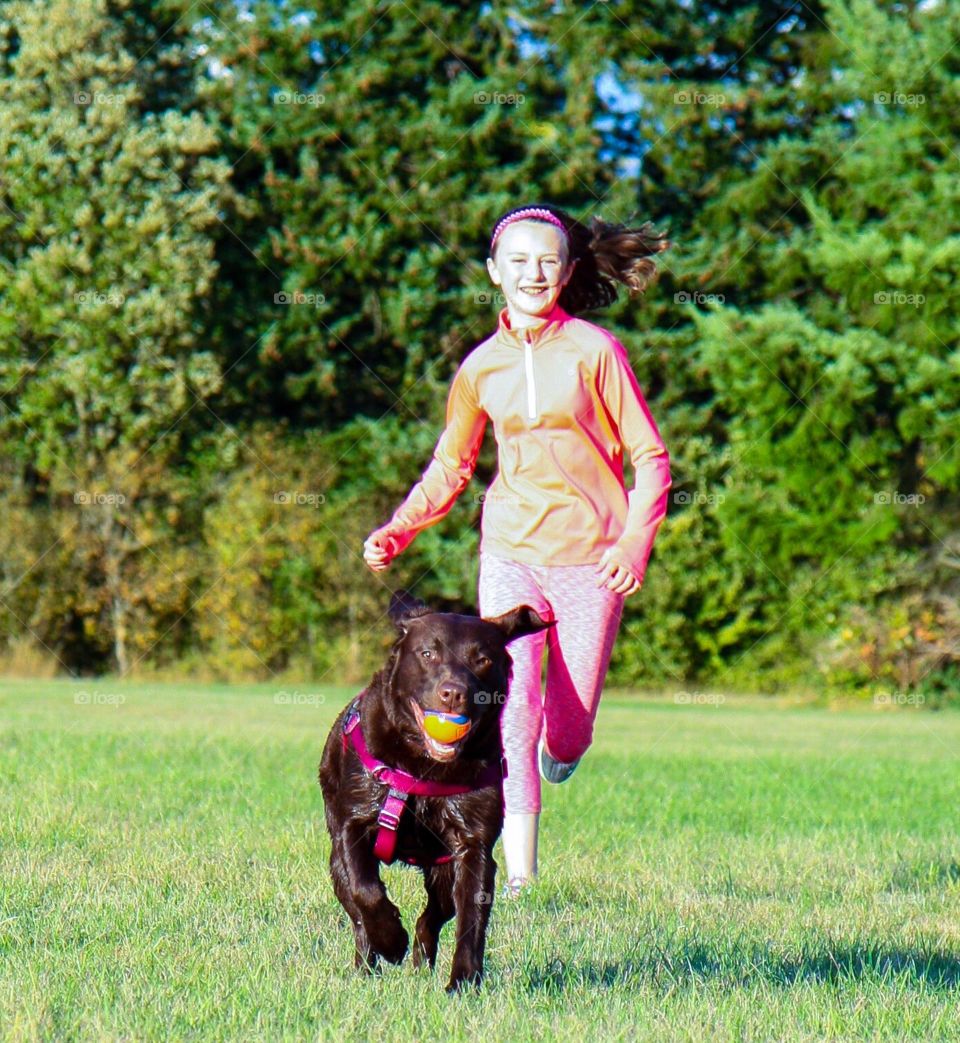 Girl running and walking with dog in a springtime park
