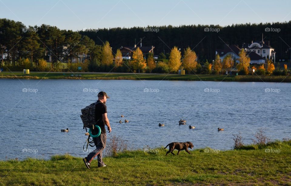 men walking with dog autumn beautiful landscape lake shore social distance