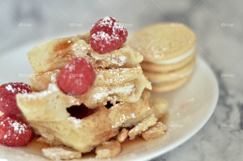 Golden double stuff Oreo cookies and a waffle with raspberries and powdered sugar