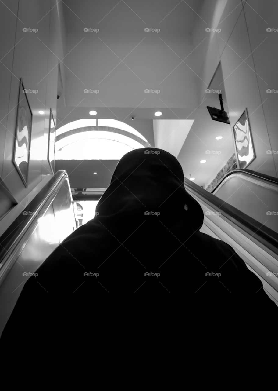 Muslim
Woman wearing black hijab climbing escalator back view 