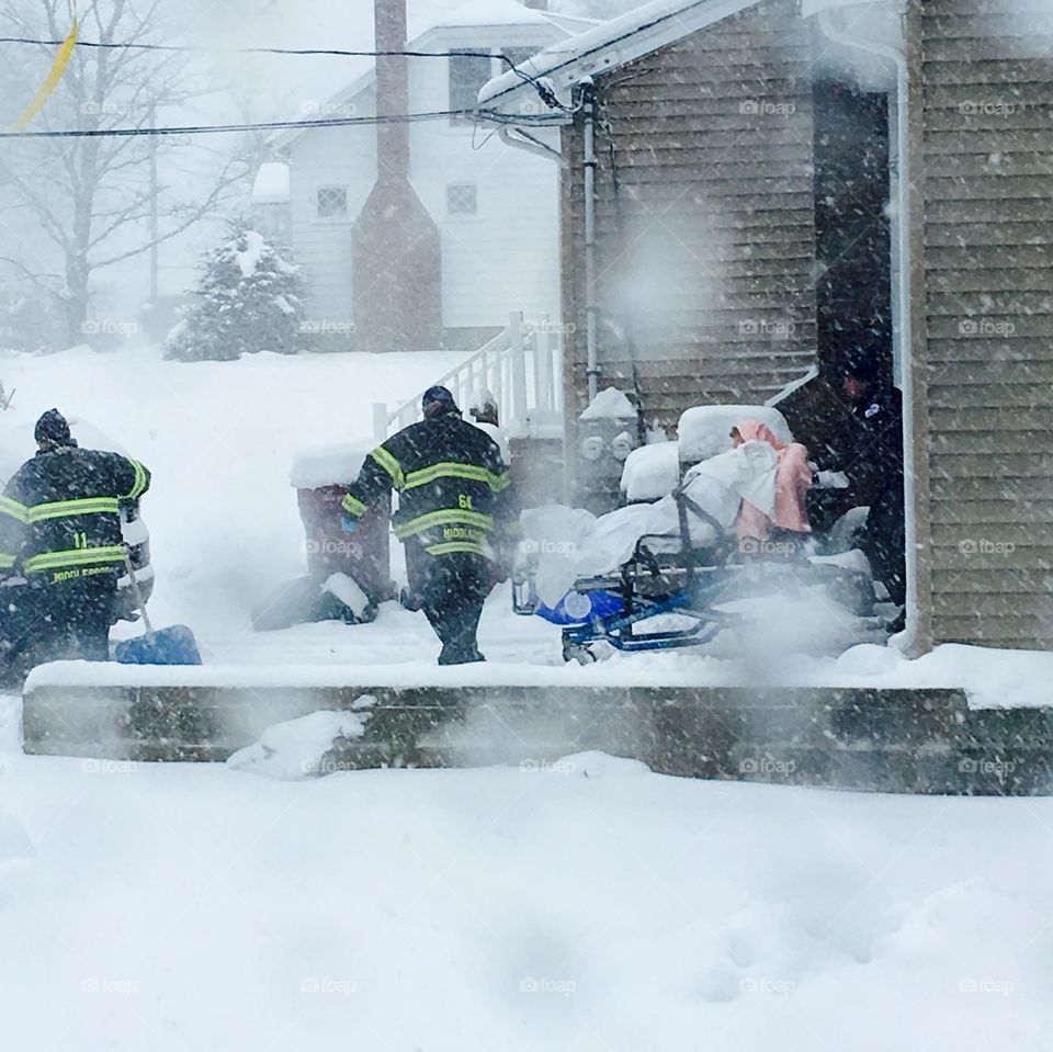 Firemen, Patient, Emergency Personnel

Ambulance waiting while one fireman shovels; another fireman pulls gurney with patient covered in pink blanket while ambulance EMT also helps get stretcher through snowstorm to ambulance!