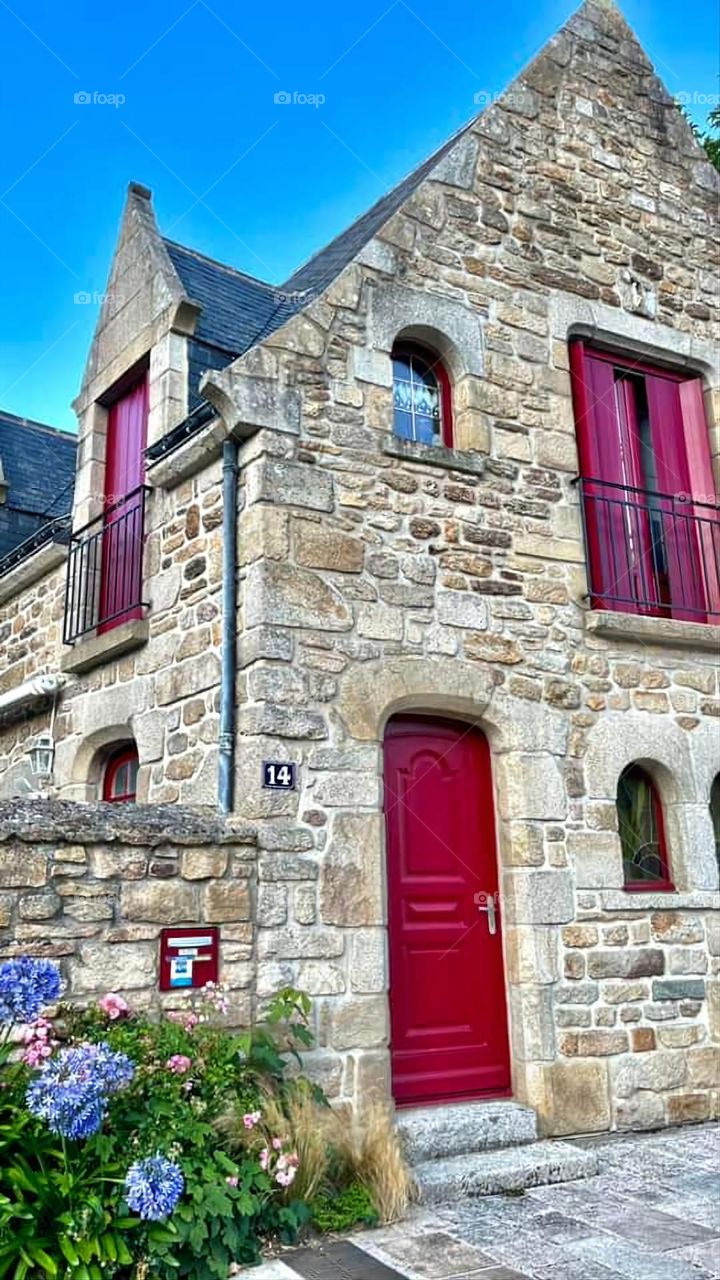 Typical Breton stone house with its slate roof and red windows, shutters and door in Saint Goustan