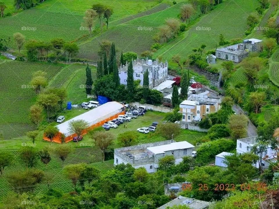 The image embodies a natural natural plate of the mountains of nature, where green agricultural stands are graded on the slopes as if they were lines of a poem, which fog harmoniously wrapped, and clouds hugged them in the mountain knife and the whis