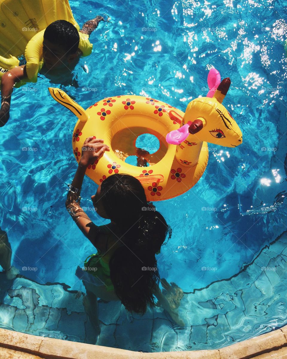 Elevated view of children playing with inflatable tube in swimming pool