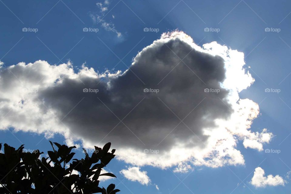 Sunlight appearing behind a grey fluffy cloud