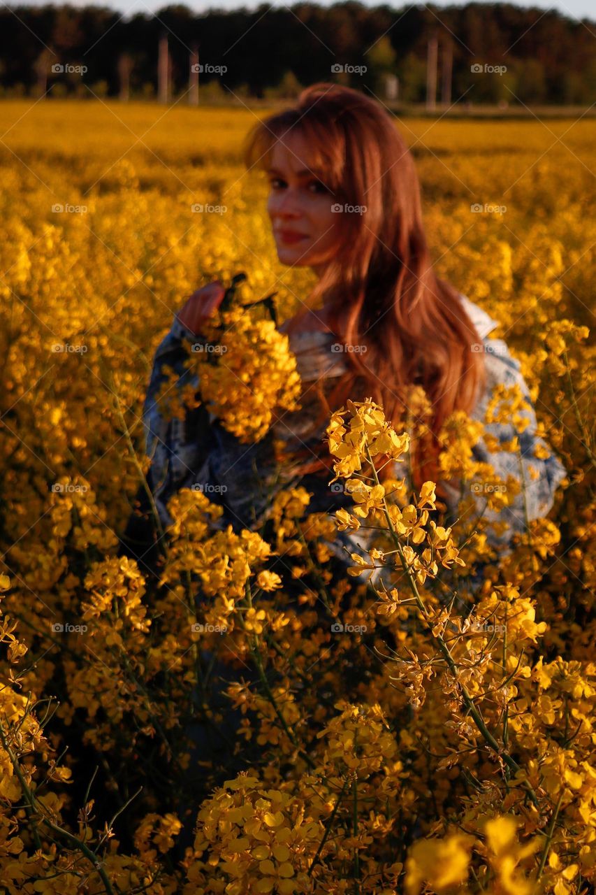 A beautiful redhead girl in the rapeseed field.
