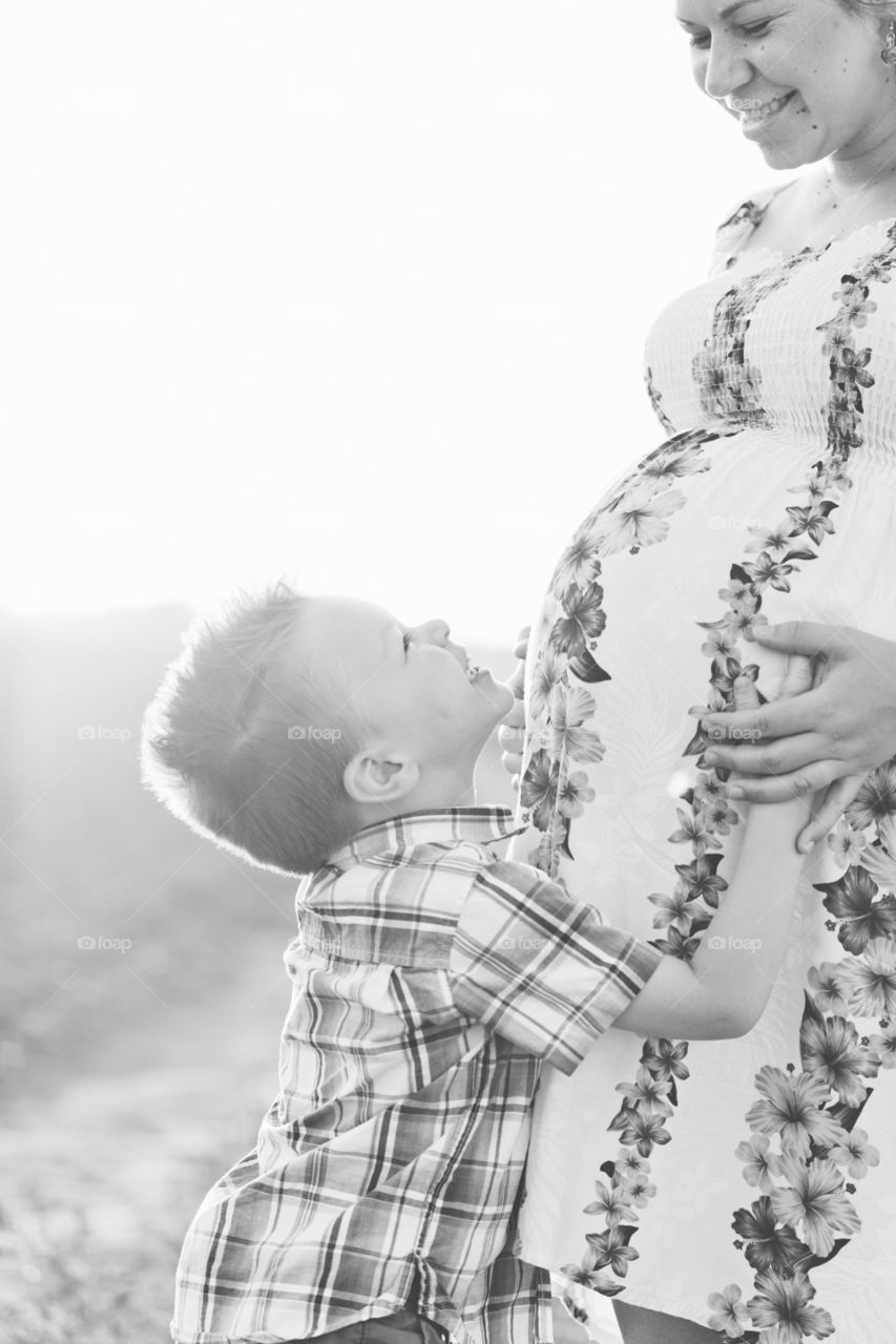 Happy toddler hugging moms pregnant belly 