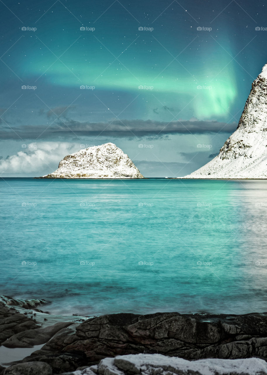 Northern lights in a wintry coastal landscape which is additionally illuminated by moonlight, in the background mountains with snow - Location: Norway, Lofoten