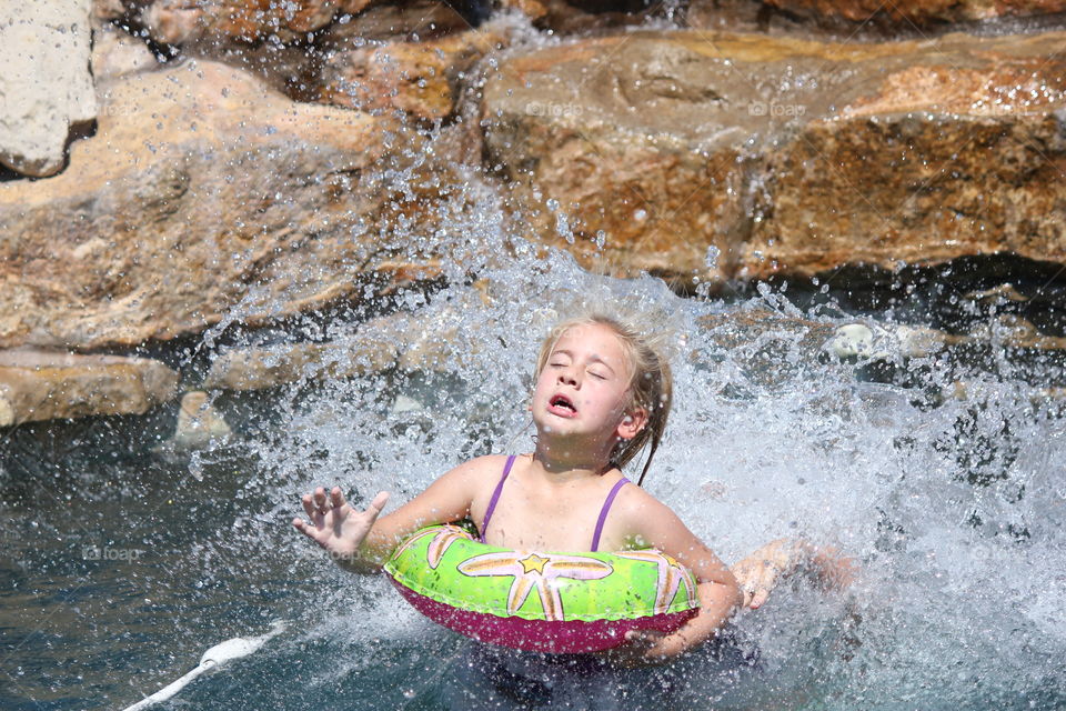 Splash zone. Girl splashing into water from a water slide