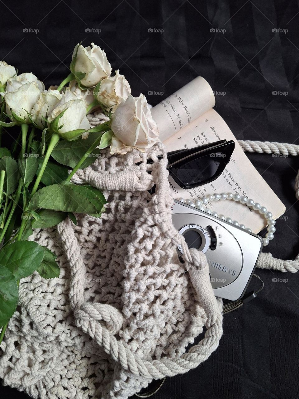 knitted vintage bag with a bouquet of flowers and retro accessories on a black background