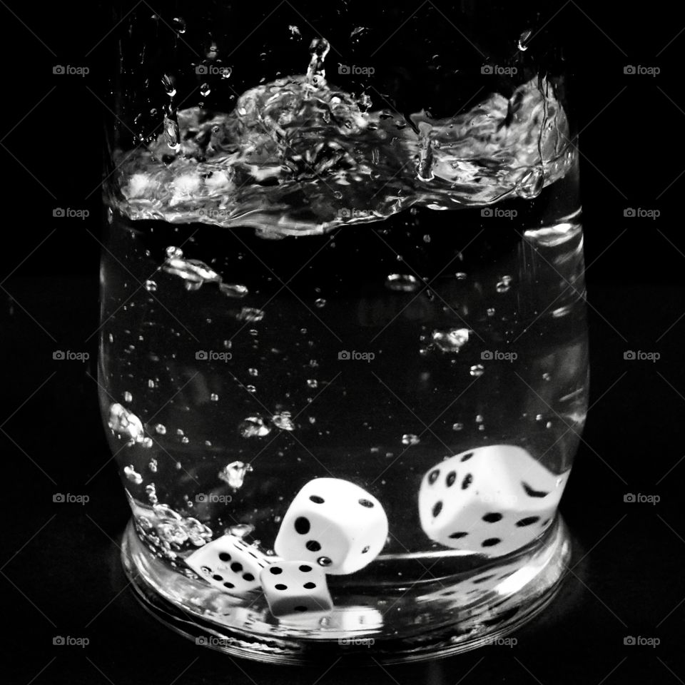 Dice in a glass of water and a black background 