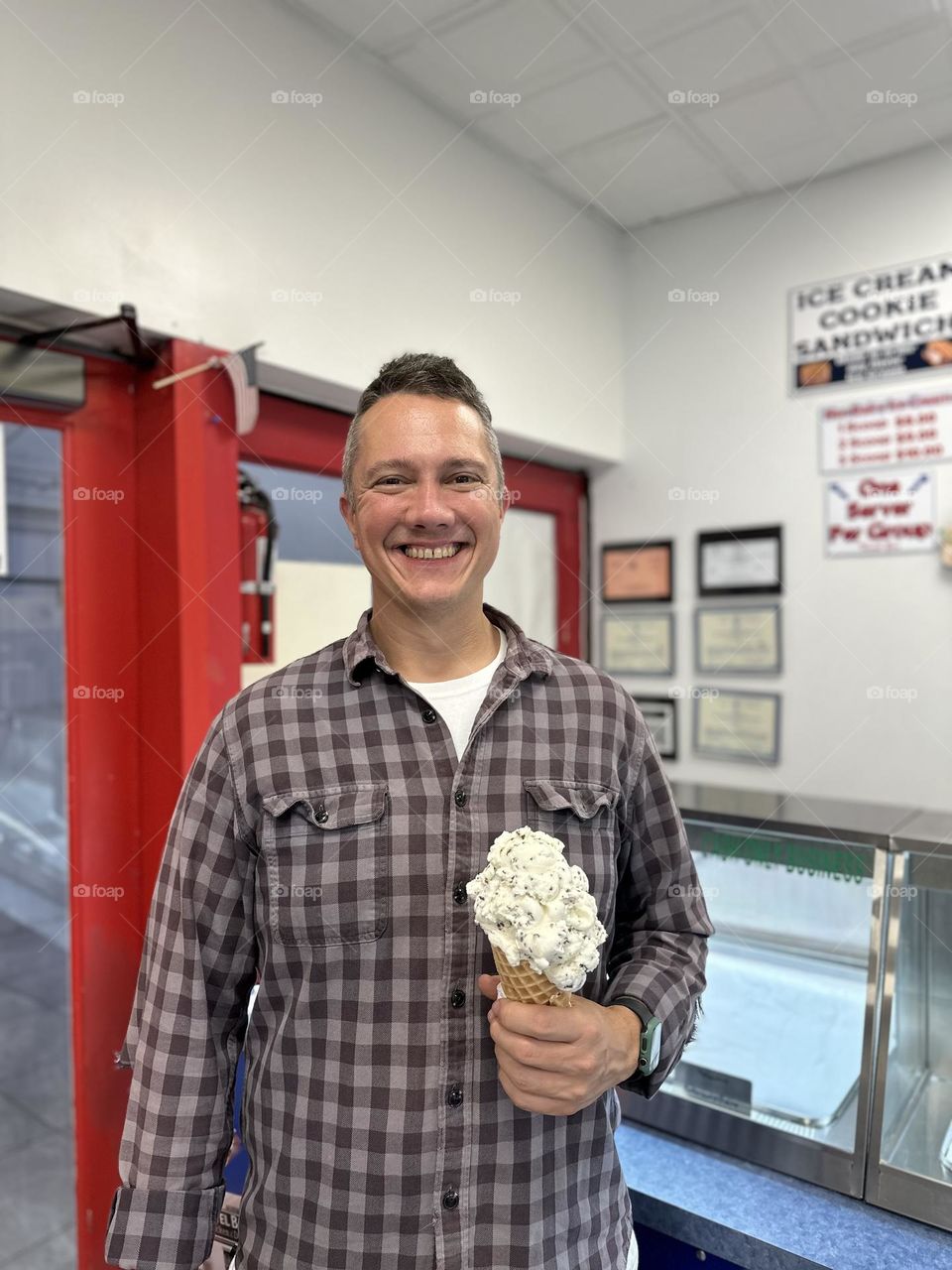 Man gets ice cream in the summertime, man holds very large ice cream cone, eating ice cream in the summer 