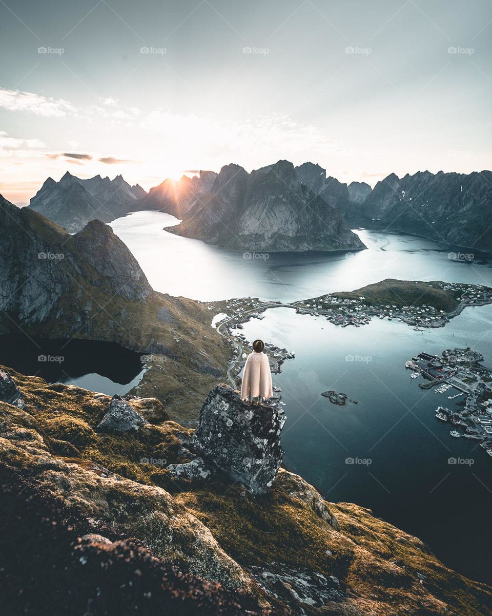 Hiker Looks Out Over Bay Surrounded By Mountains