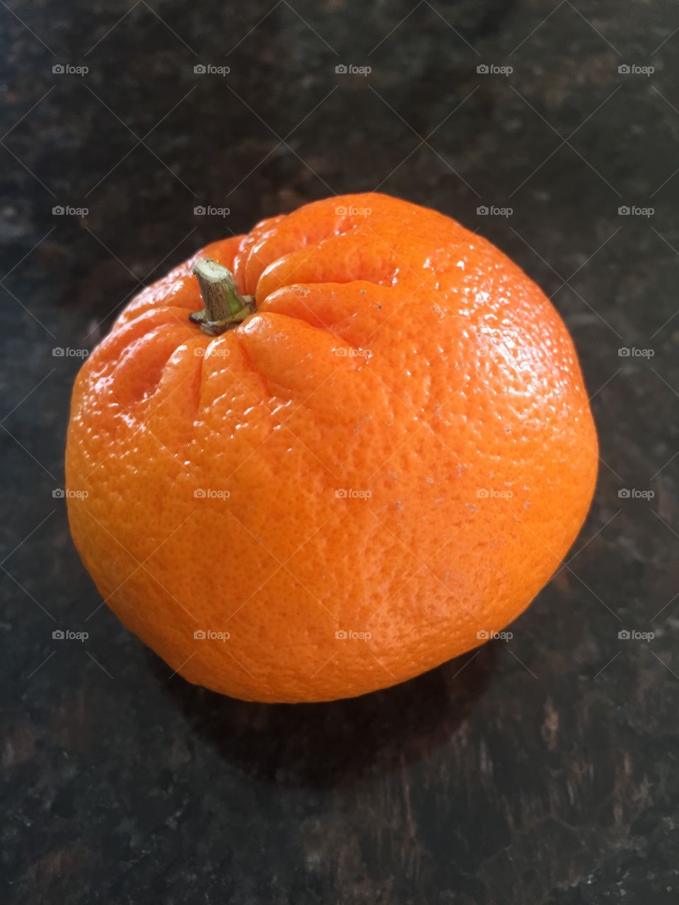 Yummy mandarin orange on black granite kitchen countertop. Three oranges a day keep doctor away? Maybe.