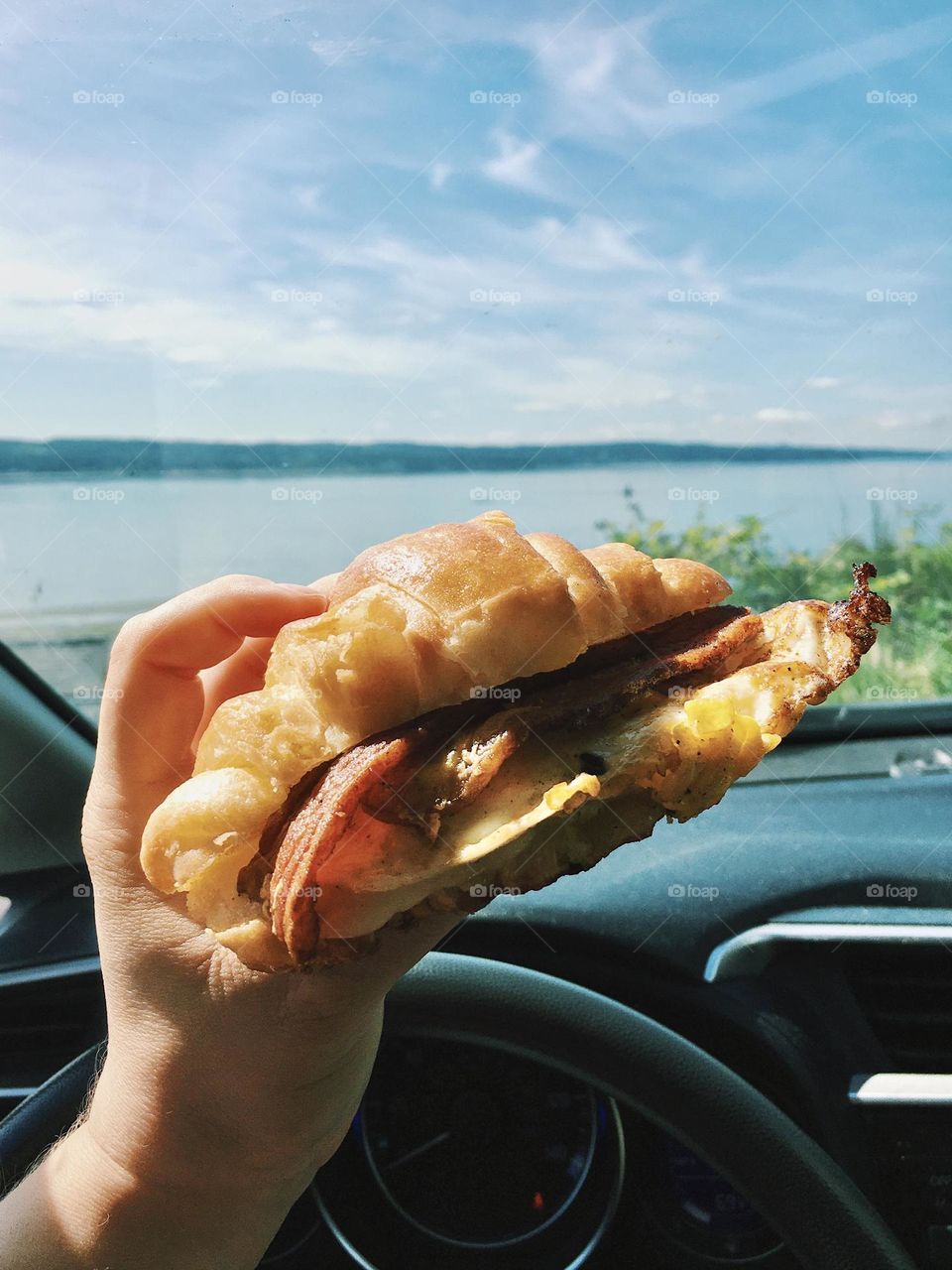Delicious croissant breakfast sandwich during a road-trip with an ocean view