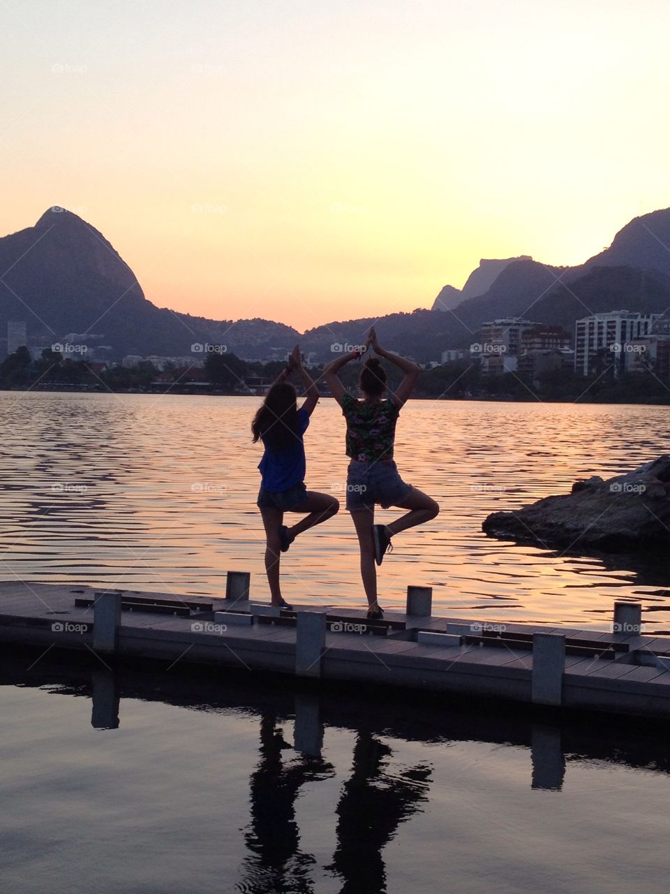 Two girls posing in a beautiful sunset by a lake
