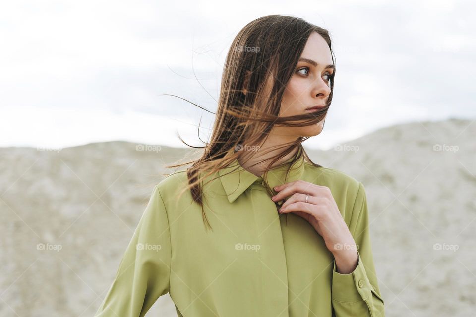 Fashion beauty portrait of young woman with long hair in green organic  shirt on desert background