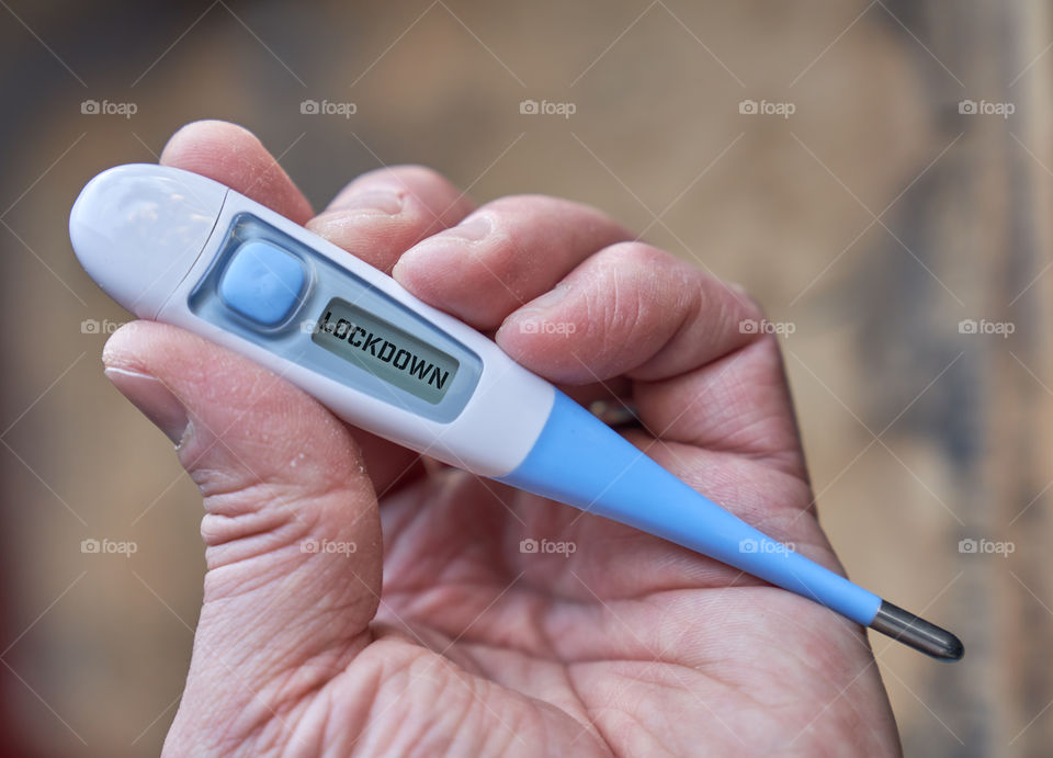 Male hand holds clinical thermometer with covid-19 text on the screen during global covid-19 or corona pandemic.
