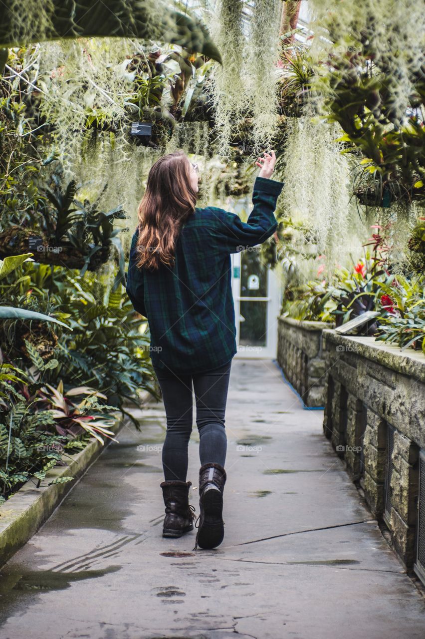 A woman walks through a botanical garden full of plants 