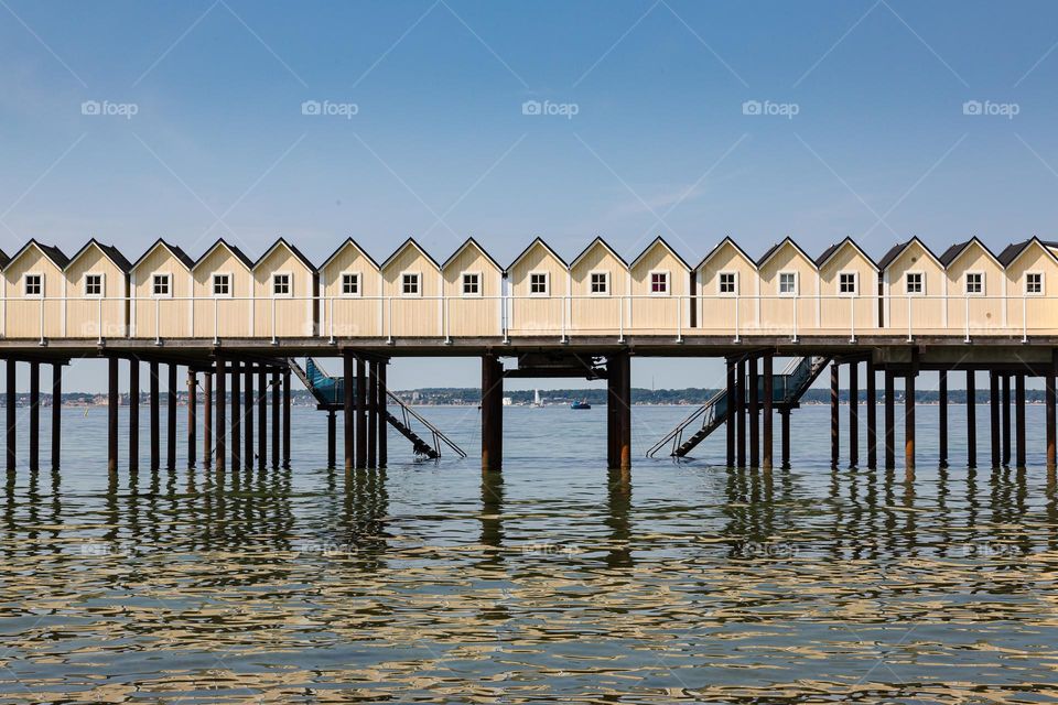 Small yellow cabins in line on a wooden pier in the ocean 