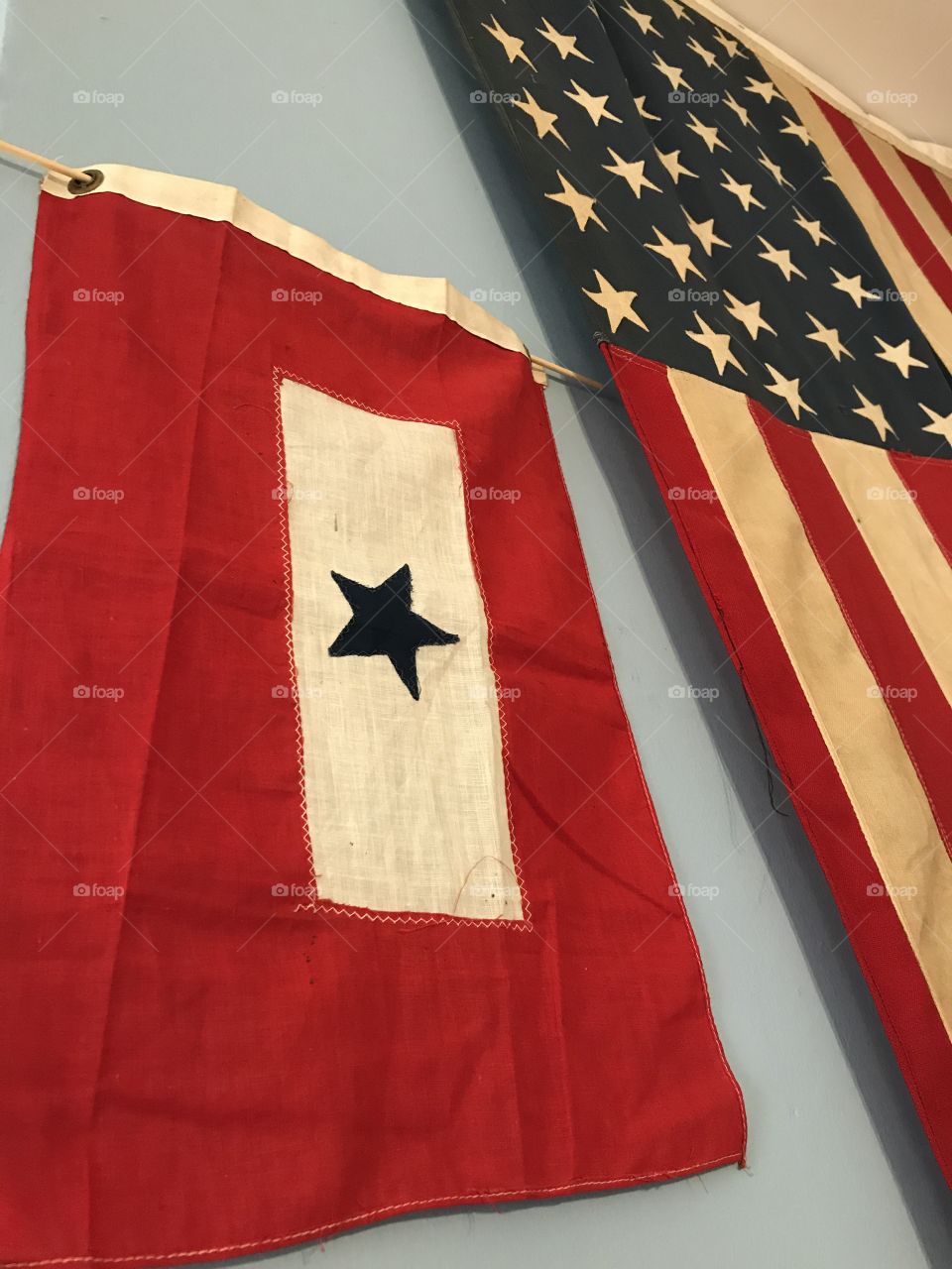 The service flag was authorized by the US department of defense during WWI for families to display when they had someone serving in the Armed Forces. The blue star represented hope. There is also one with a yellow star that represented sacrifice. Next to it hangs a 48 star flag.