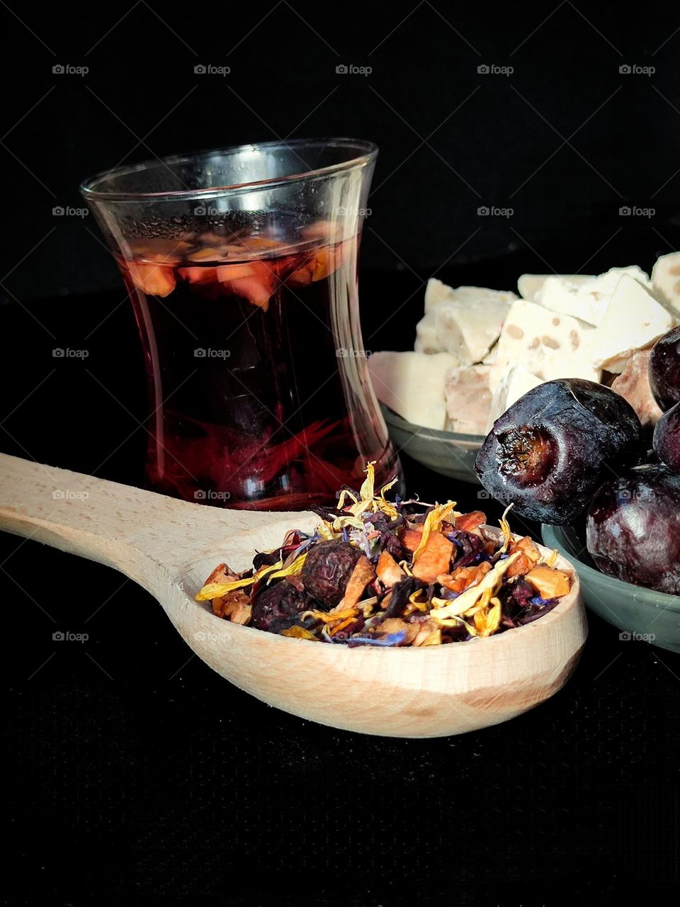 Composition. Tea drinking in Baku style.  A wooden spoon with a mixture of black tea and various herbs, a glass of "armuda" with tea, a saucer of dates and a saucer of walnut baklava