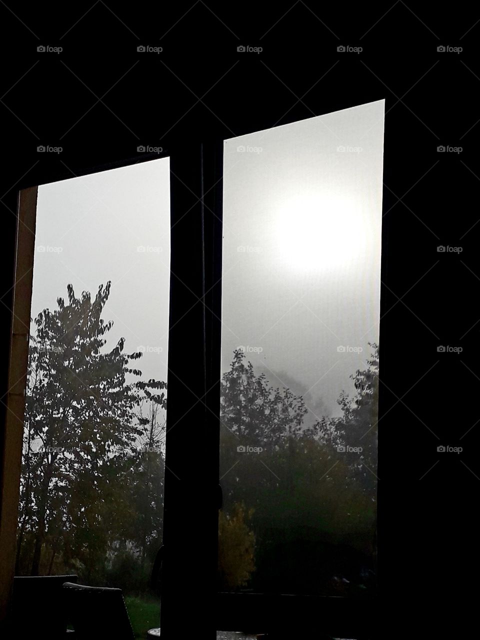 misty autumn morning through the window  with sun behind the mist