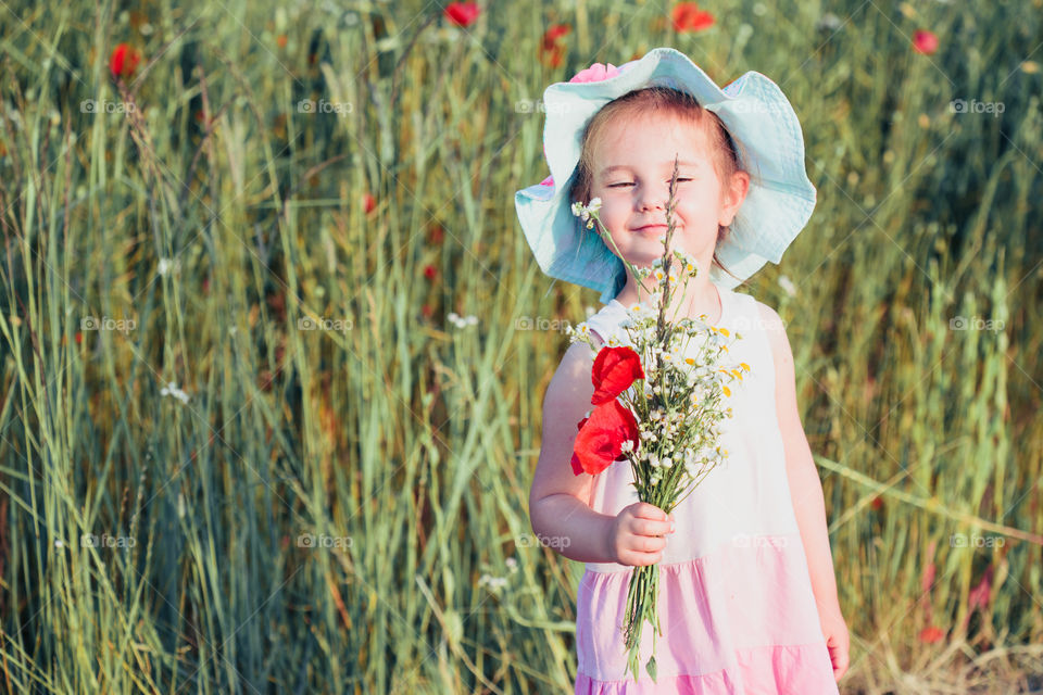 Lovely little girl in the field of wild flowers. Cute girl picking the spring flowers for her mom for Mother's Day in the meadow. Spending time close to nature