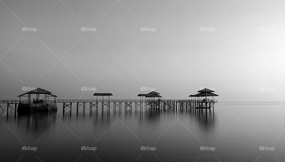 a wooden pier in the middle of the beach is useful for fishermen