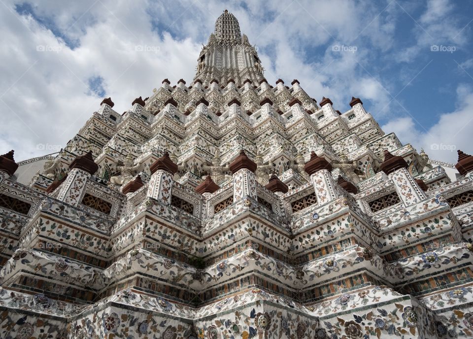 Symmetry composition leading line to top of famous pagoda of  Temple of  Dawn (Wat Arun) on blue sky background in Bangkok Thailand 