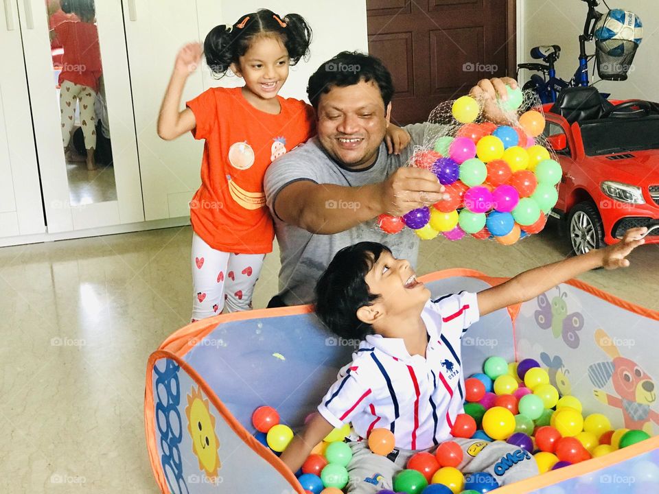 Father and kids playing together, father pore balls into ball pit and kids enjoying a lot.