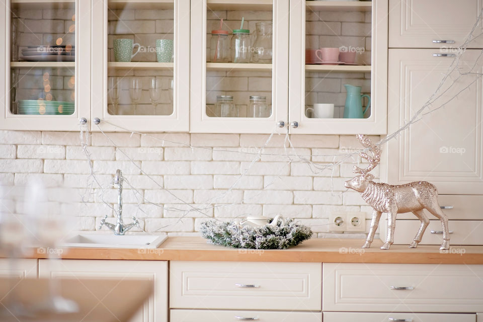 Festive winter cozy kitchen interior with garlands, decorations and gifts.  Christmas dinner at the decorated table.