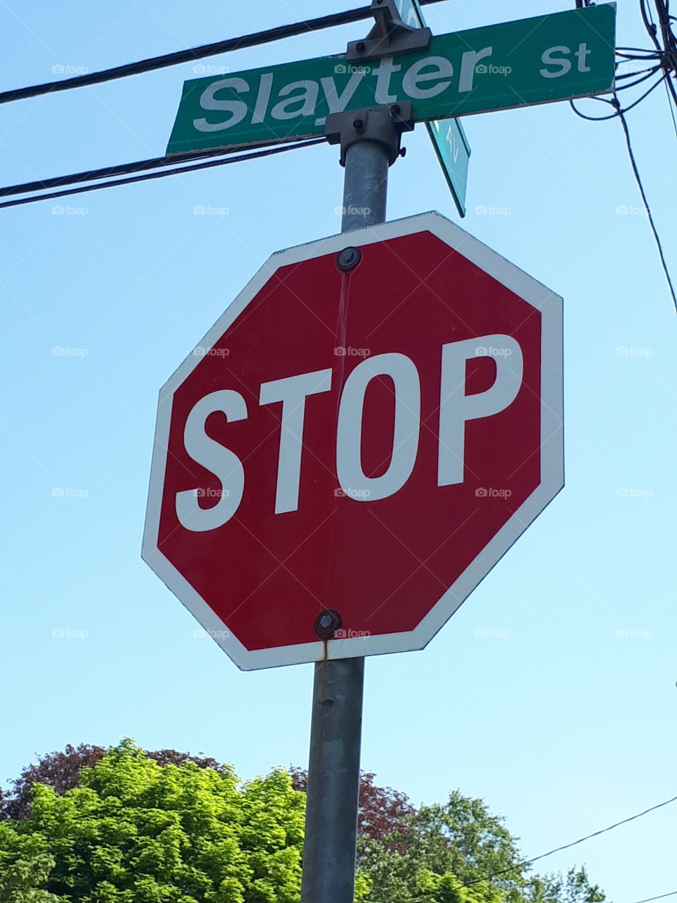 a red and white stop sign under some utility wires