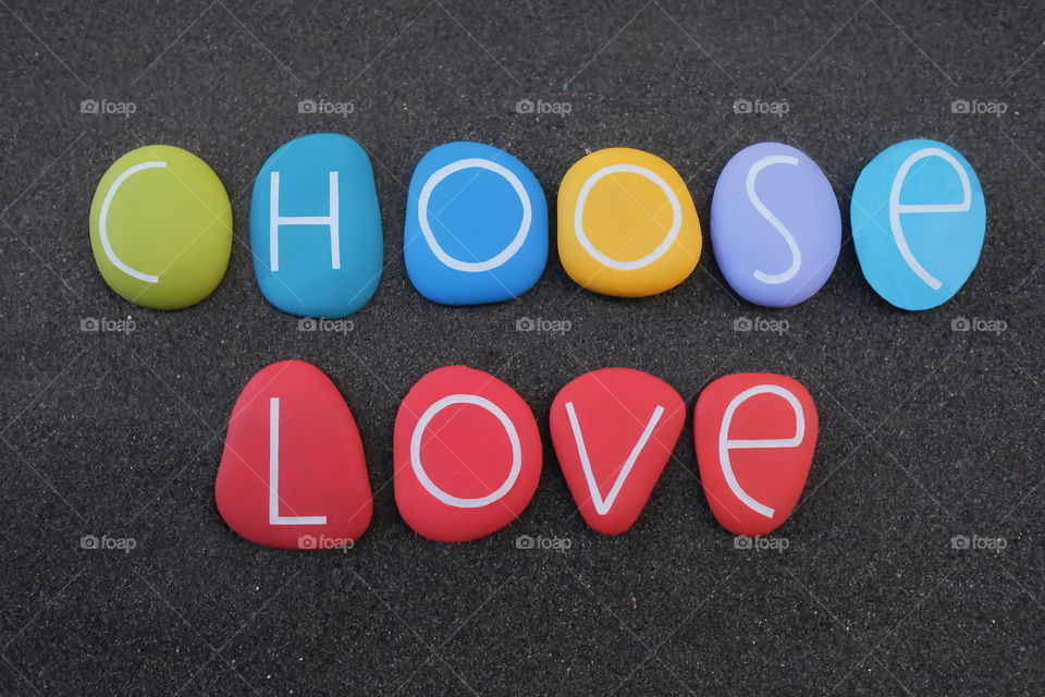 Choose love phrase composed with multi colored stone letters over black volcanic sand