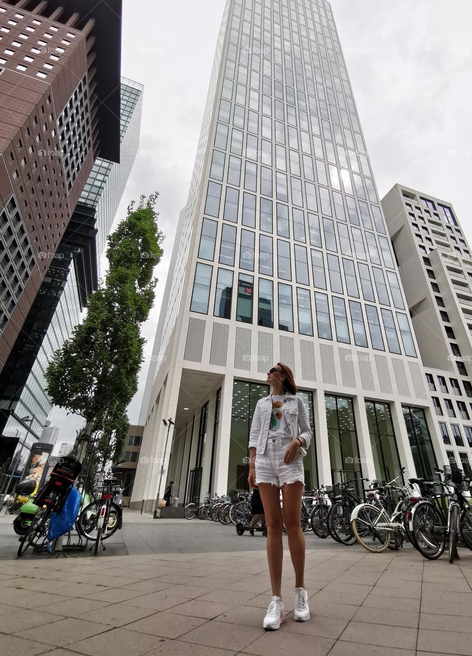 Women in the city. Skyscrapers and people. Architecture in the city. Bicycles on the street. Street photo. Before rain. Shooting from below. Unusual shooting angle. Down up. From the ground up.