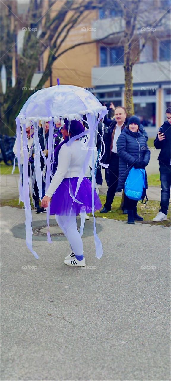 An umbrella with ribbons, tassels and pompons makes this outfit work for the carnival parade in „Bad Füssing“, „Bavaria“, Germany on „Mardi Gras“ or „Fat Tuesday“, last day of the festivities known here as „Fasching“. 2024. Hypnotic Productions