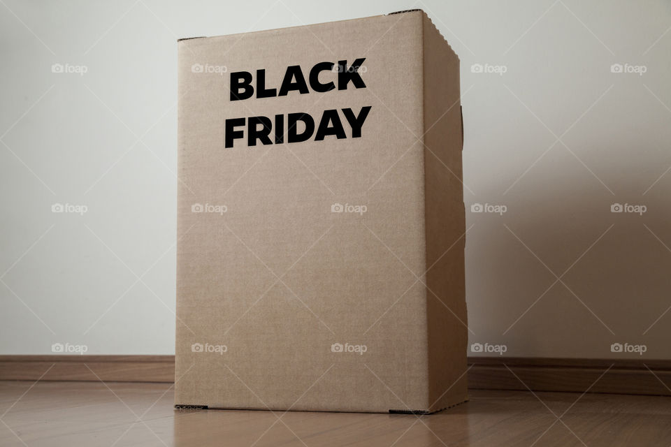 Cardboard box with black friday order written on the box placed on the floor in an empty room with a neutral background. delivery concept. economy concept. black friday concept. shopping concept.