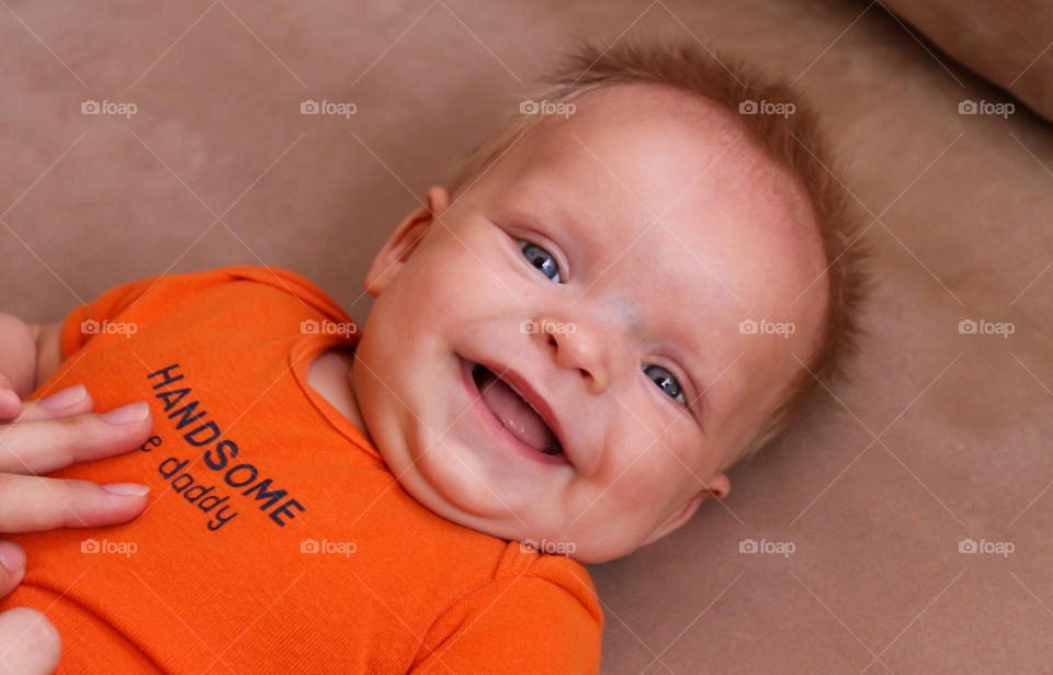 Baby boy lying on bed and laughing