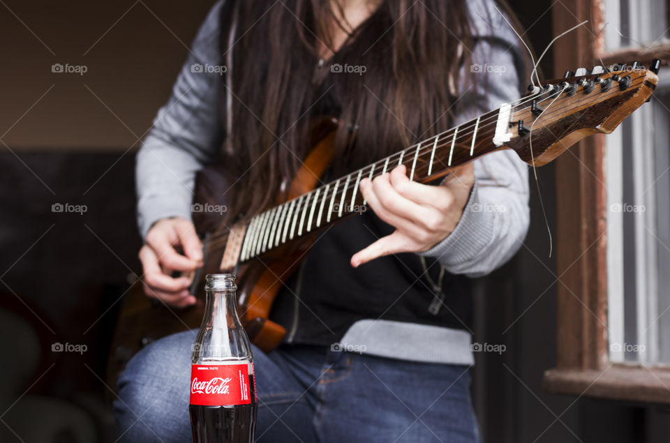 Guitarist woman playing a guitar and Coca Cola drink