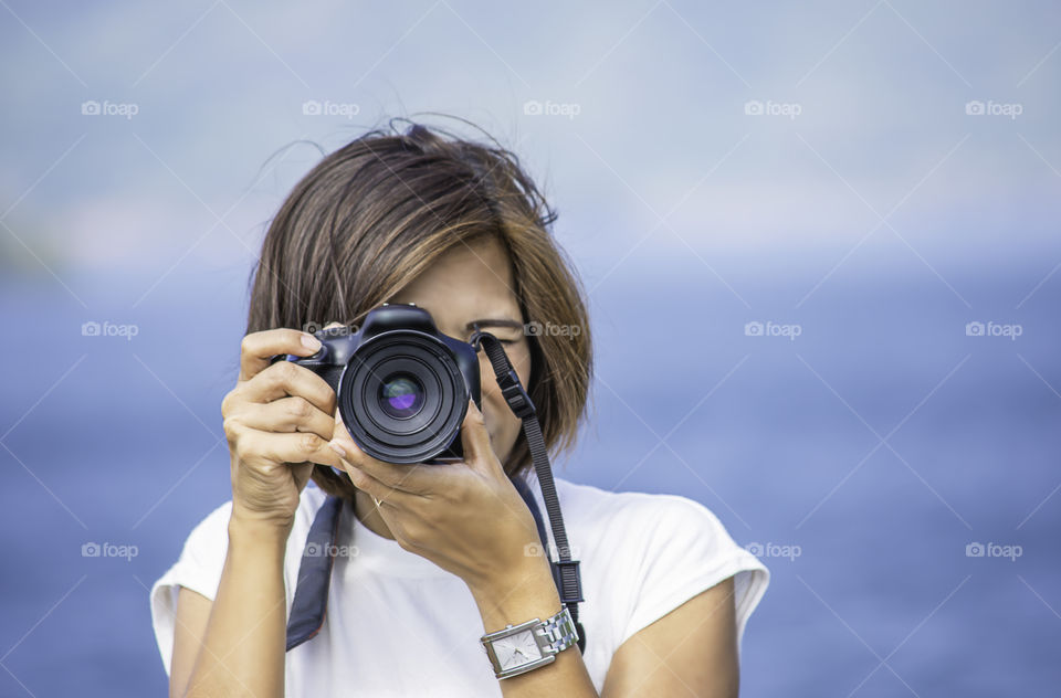 Hand woman holding the camera Taking pictures background Kaeng Krachan dam phetchaburi , Thailand.