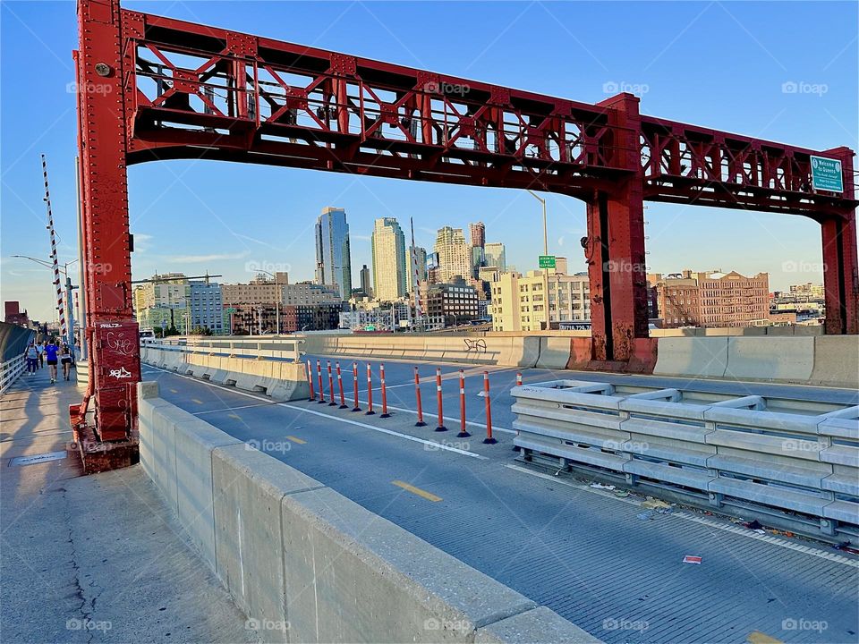 This is the red ornamented metal gate spanning across the various lanes of the “Pulaski Bridge” at “Newtown Creek” that connects “Greenpoint”, Brooklyn to LIC, Queens, the direction in which we are currently heading. 2024. Hypnotic Productions