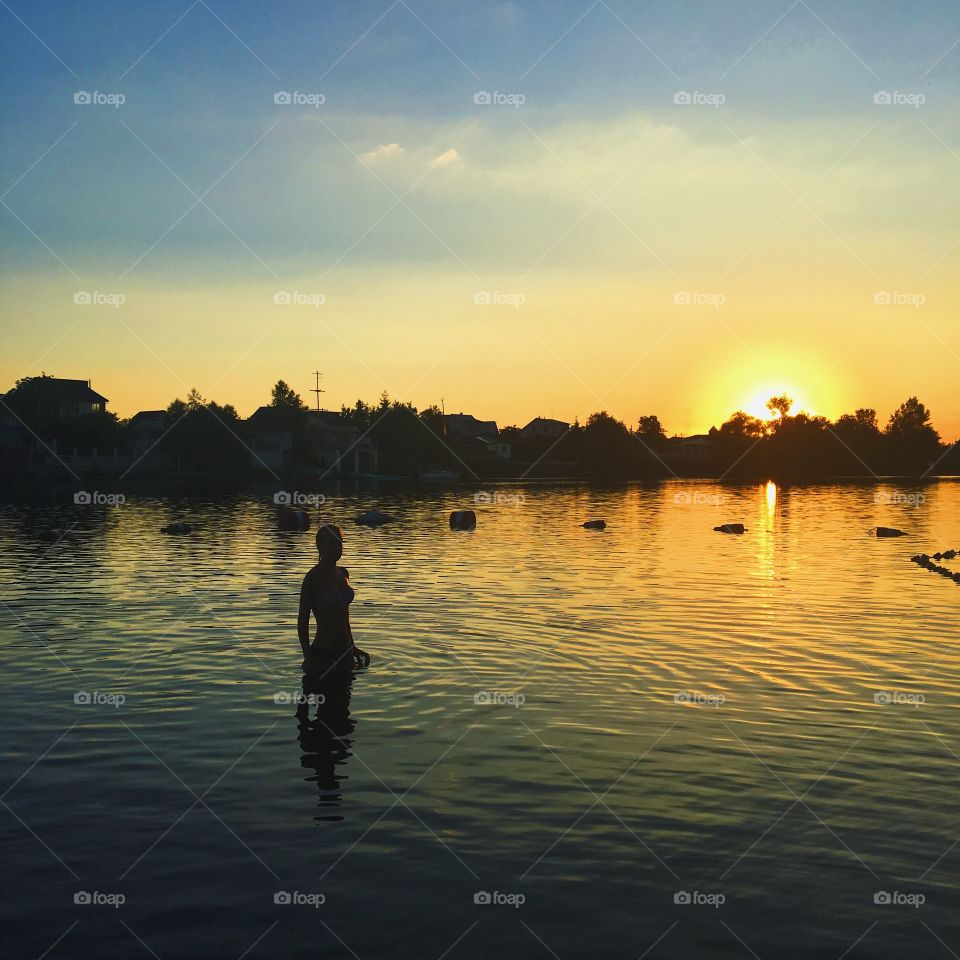 Girl comes out of the water at sunset 